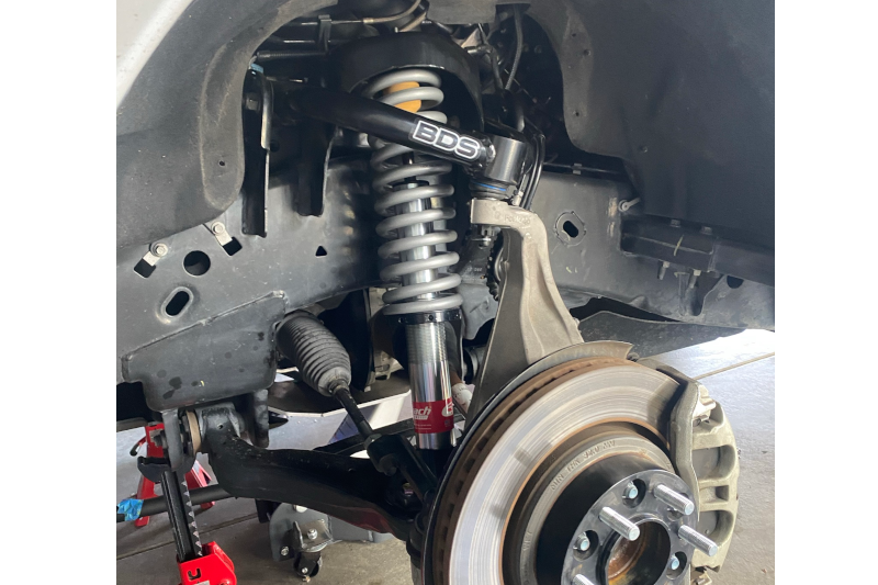 Eibach Pro-Truck coilover being installed in a Ford F150 front strut bay with the sway bar end link disconnected