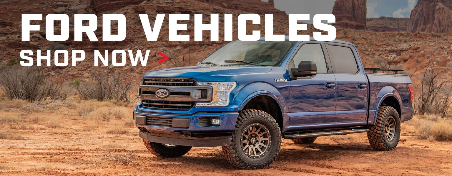 Shop Ford Vehicles. Lifted blue Ford F-150 on aftermarket wheels in desert terrain.